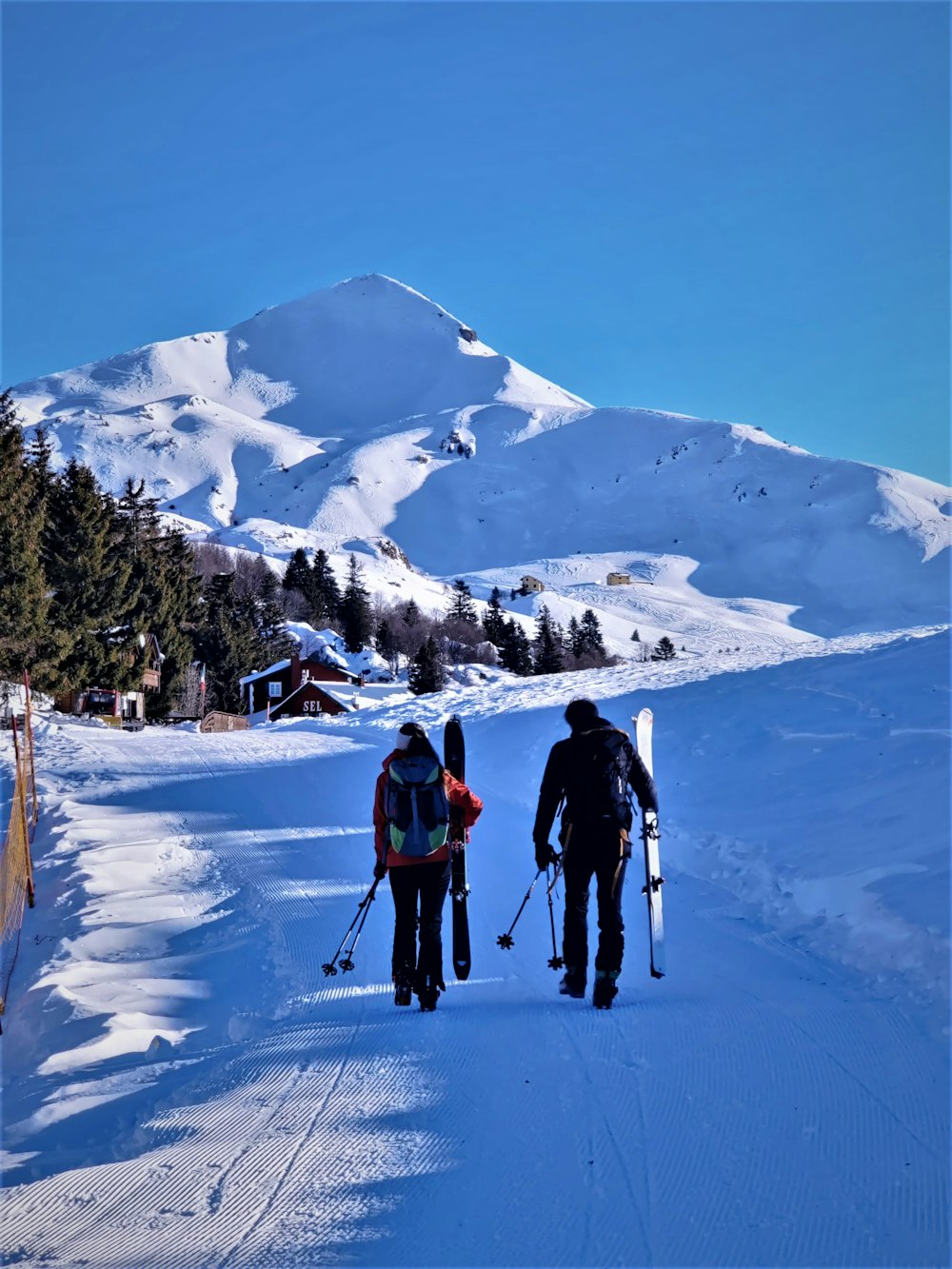 Mensen die met ski's in hun hand aan het lopen zijn naar een huisje