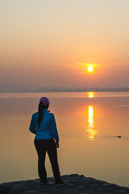 A calm person standing at sunrise looking hopeful towards a new day.