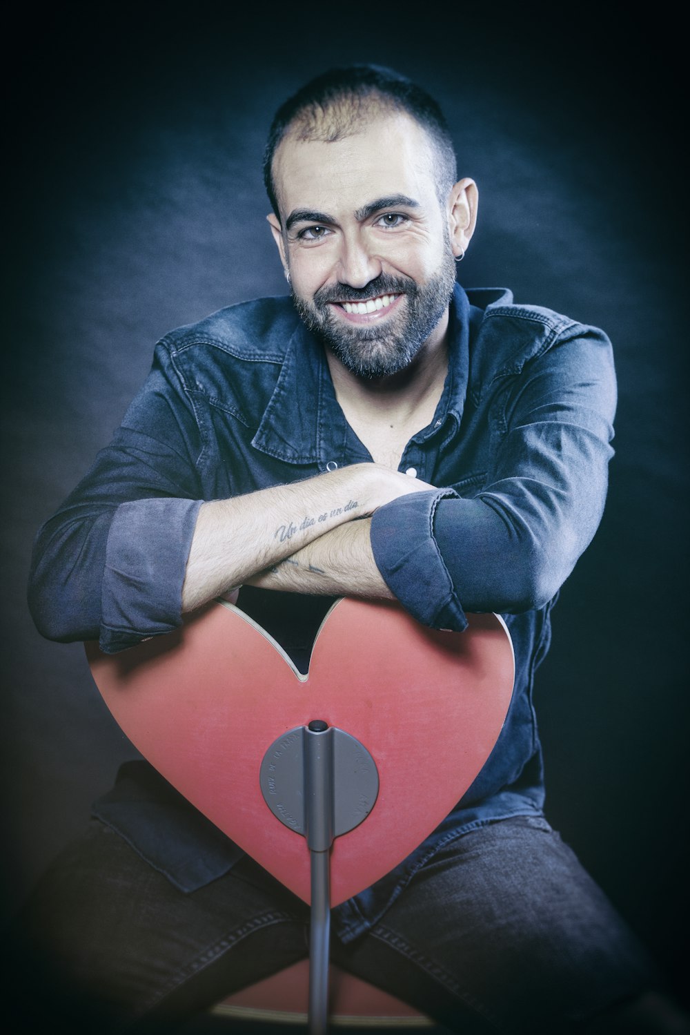 man in blue dress shirt holding red heart pillow