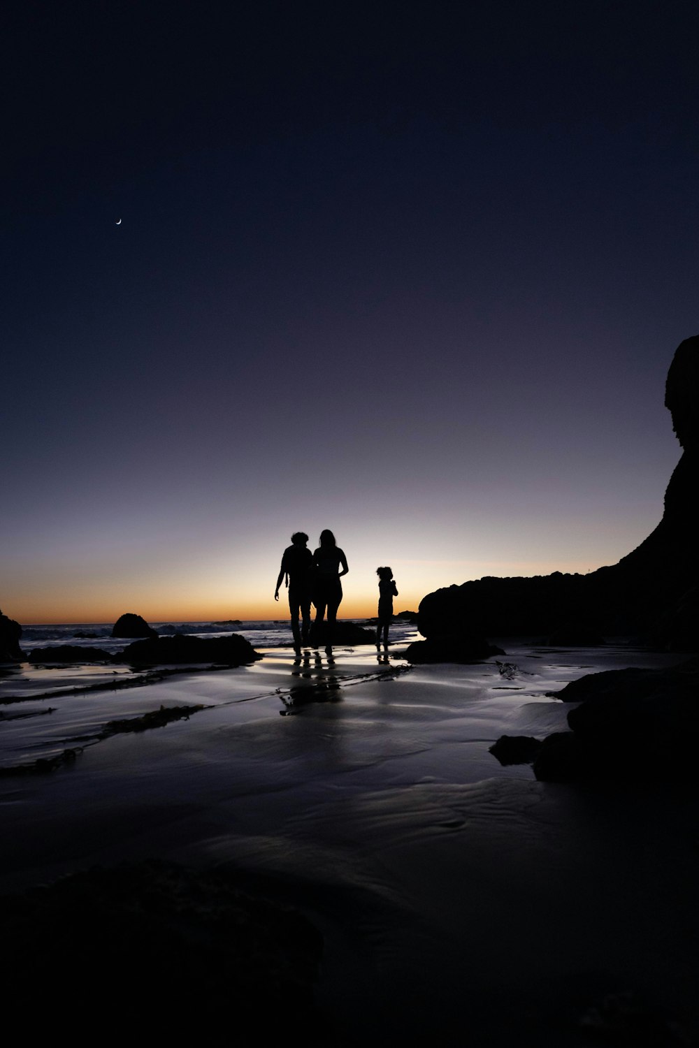 日没時にビーチに立つ2人のシルエット