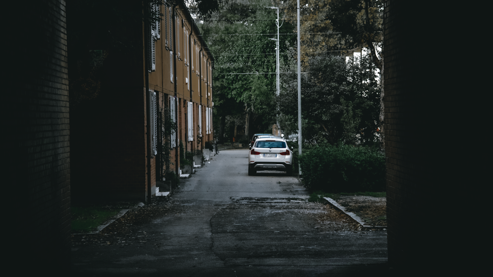 white car parked beside brown building during daytime