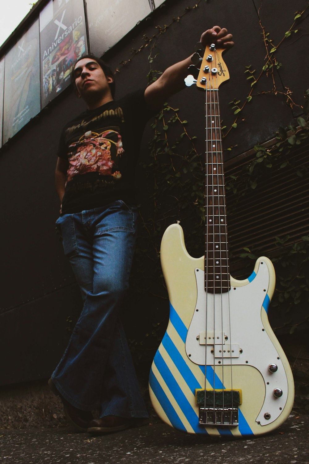 man in black crew neck t-shirt and blue denim jeans playing blue and white electric