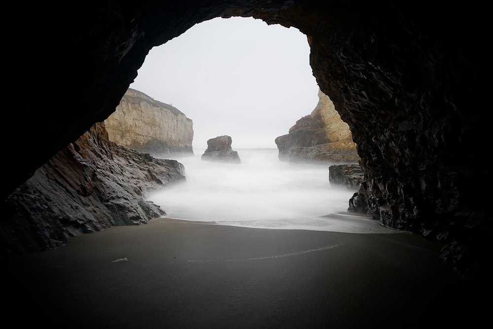 brown cave near body of water during daytime