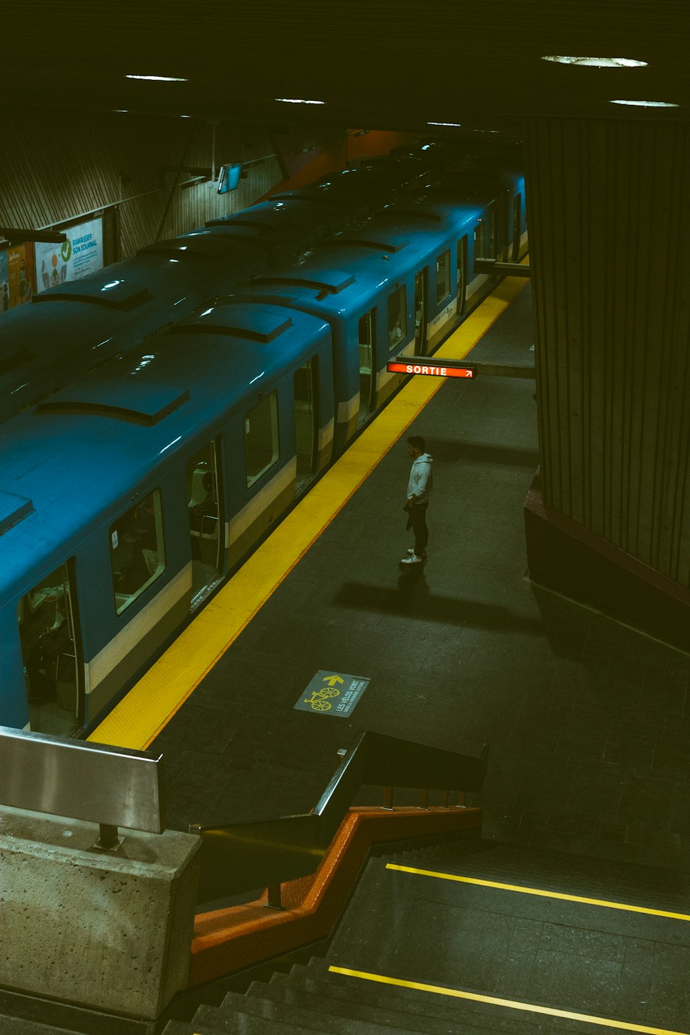 man in white shirt and black pants standing beside blue train