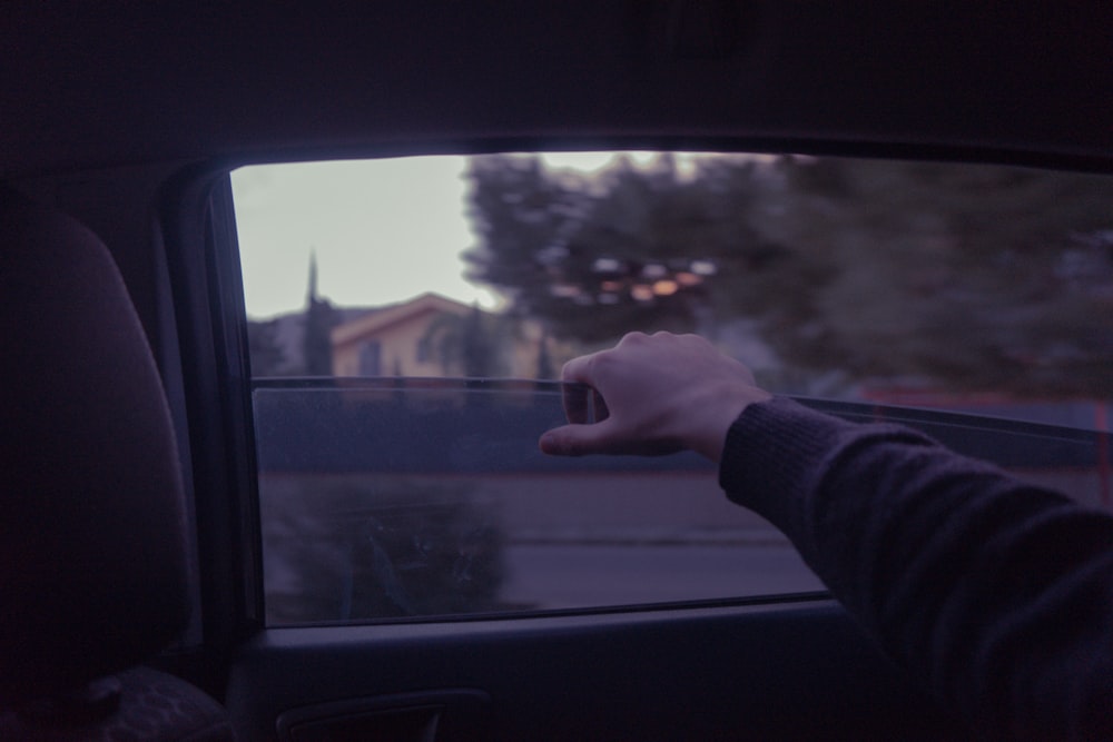 person in gray long sleeve shirt holding car window