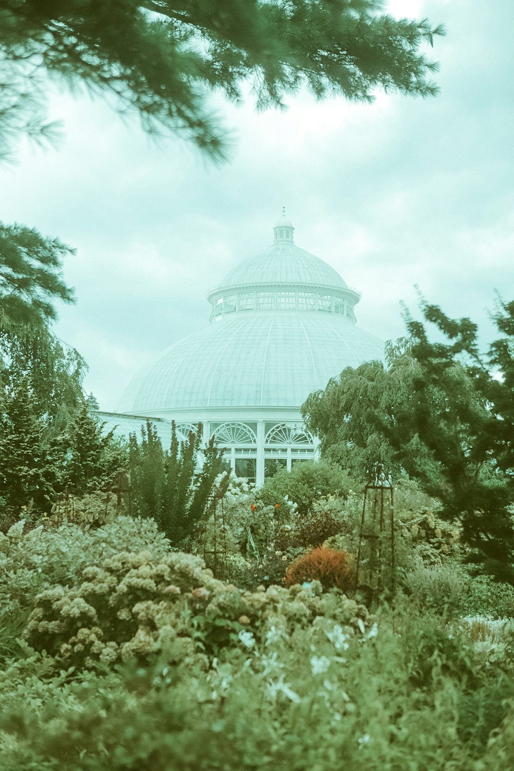 white and green dome building surrounded by trees under white clouds and blue sky during daytime