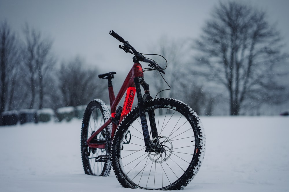 Vélo de montagne hardtail rouge et noir sur sol enneigé pendant la journée