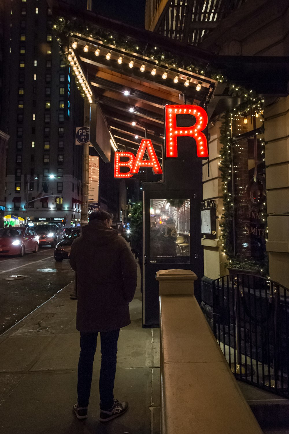 man in black coat standing near store during night time