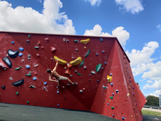 A team installing a vibrant climbing wall under a bright sky in an urban setting.