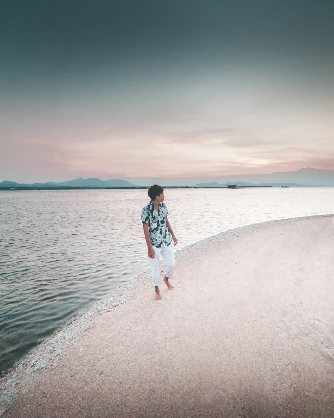 woman in white and black dress standing on white sand near body of water during daytime