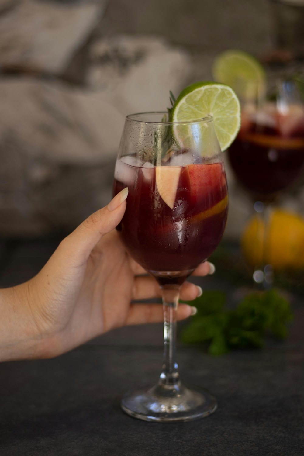 person holding clear wine glass with red wine