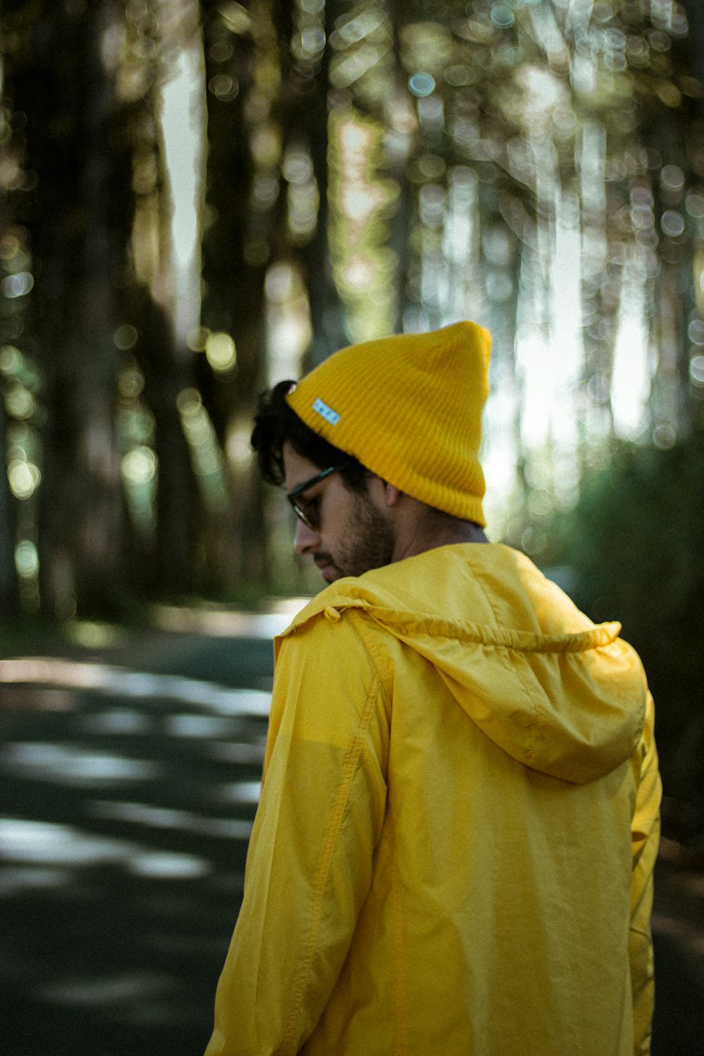 Homme en sweat à capuche jaune et bonnet en tricot noir debout dans la forêt pendant la journée