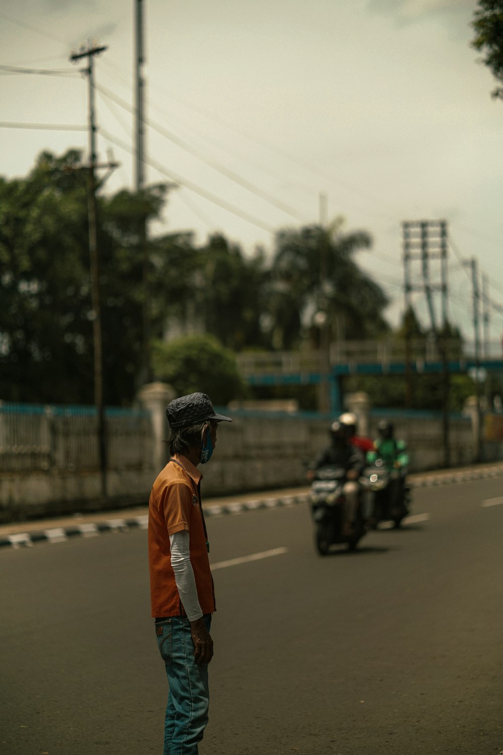 man in orange jacket and black helmet standing on road during daytime