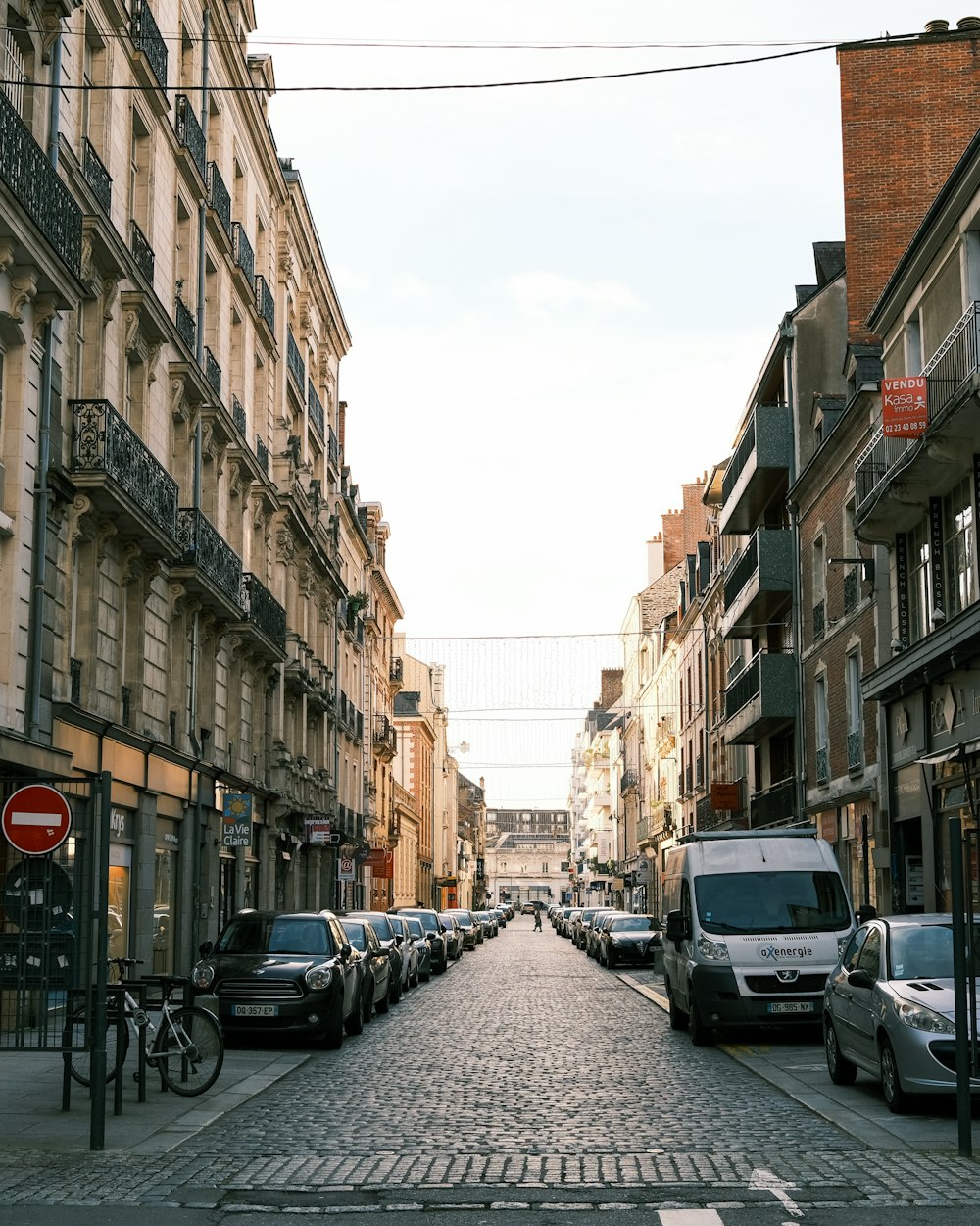 cars parked on side of the road in between buildings during daytime