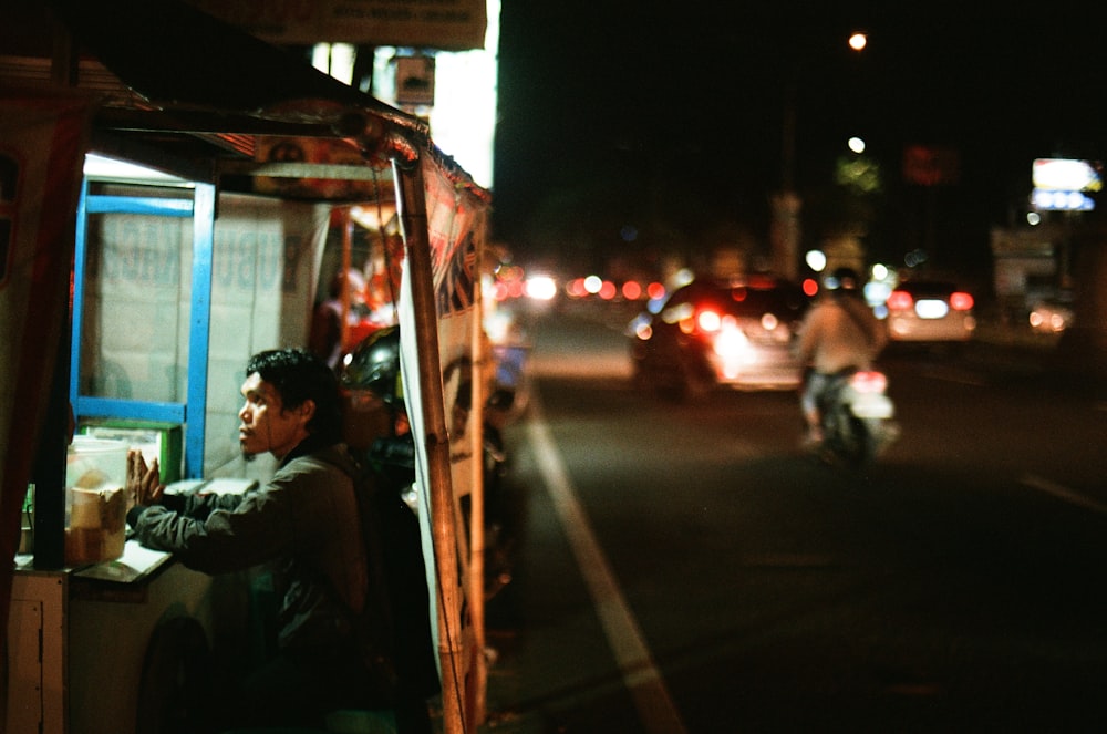 man in white shirt sitting on chair near car during night time