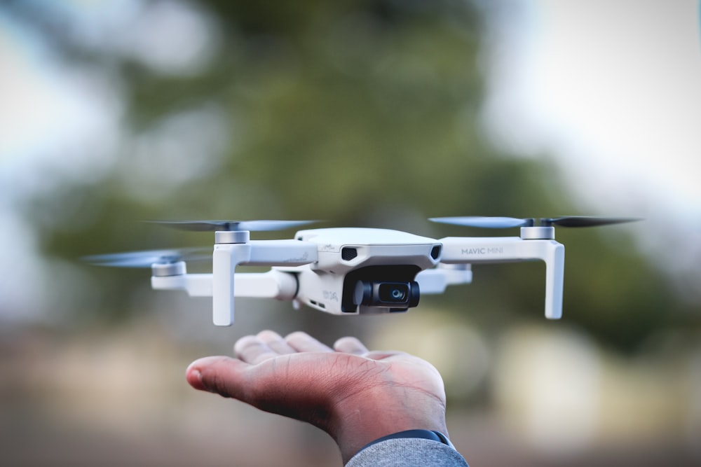 Persona sosteniendo un dron blanco y negro