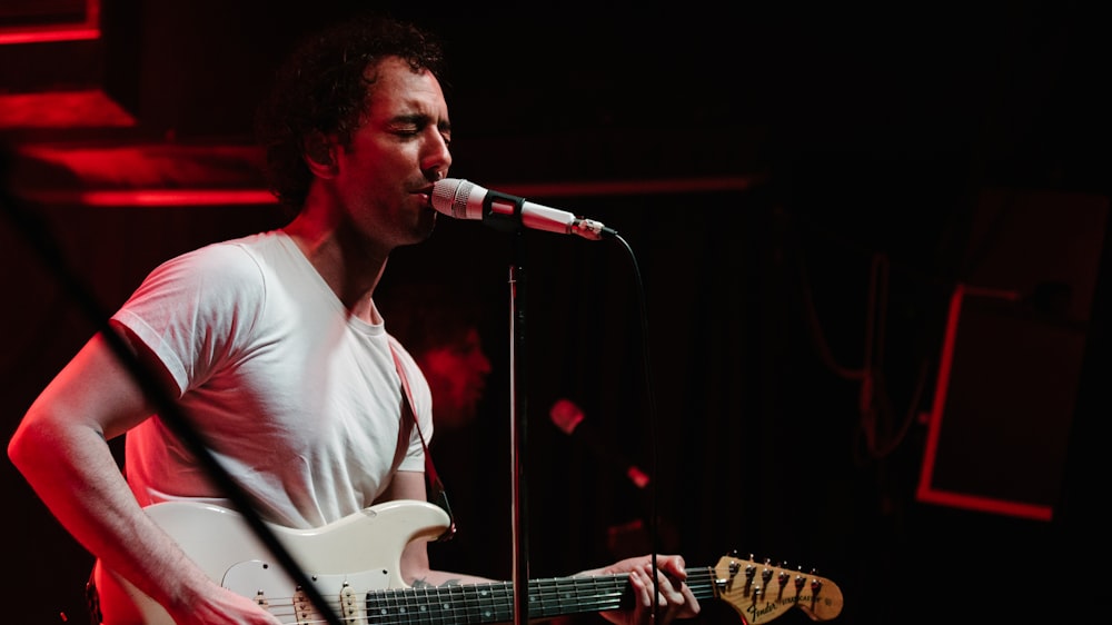 man in white crew neck t-shirt playing electric guitar