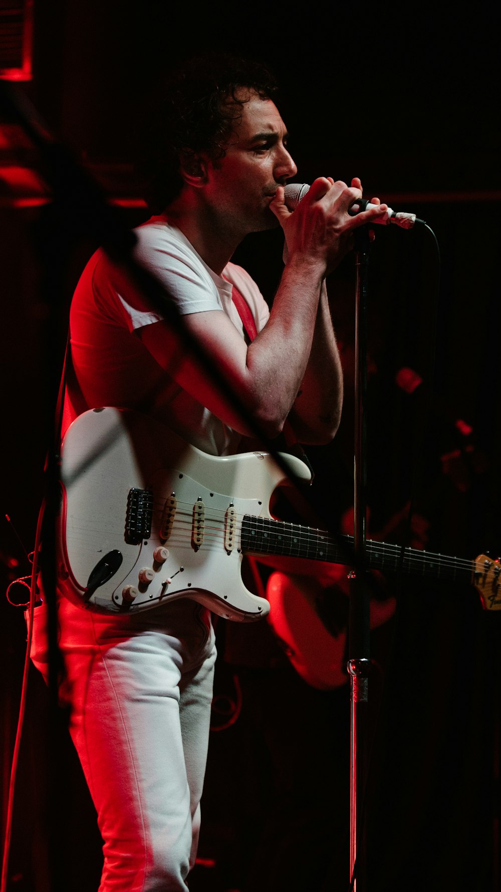 man in red t-shirt playing electric guitar