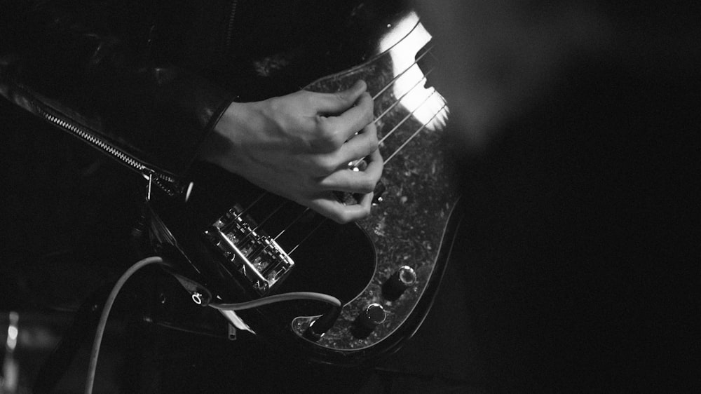 grayscale photo of man playing electric guitar