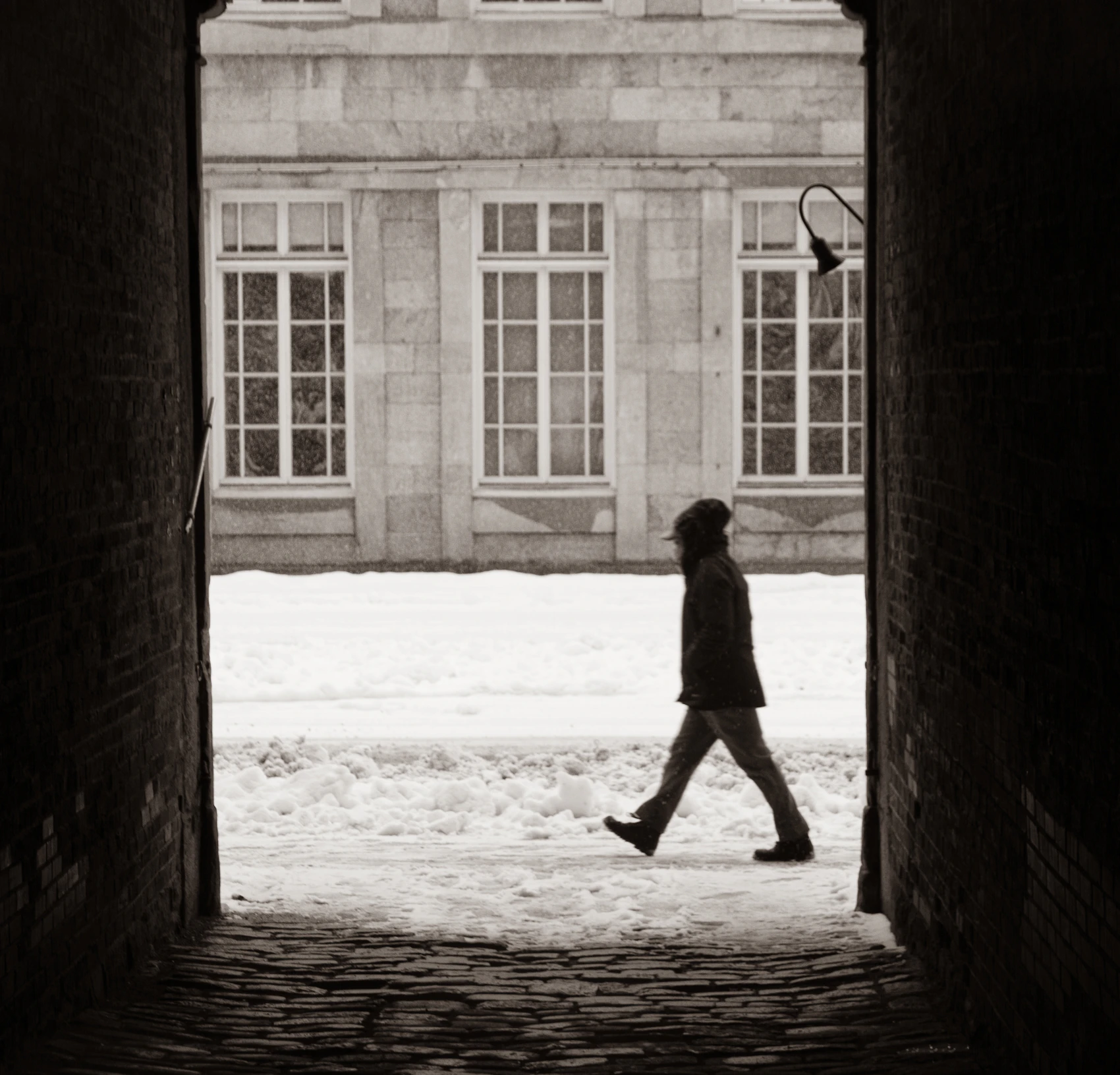 A pedestrian crossing a snow-covered historic street in Old Montréal