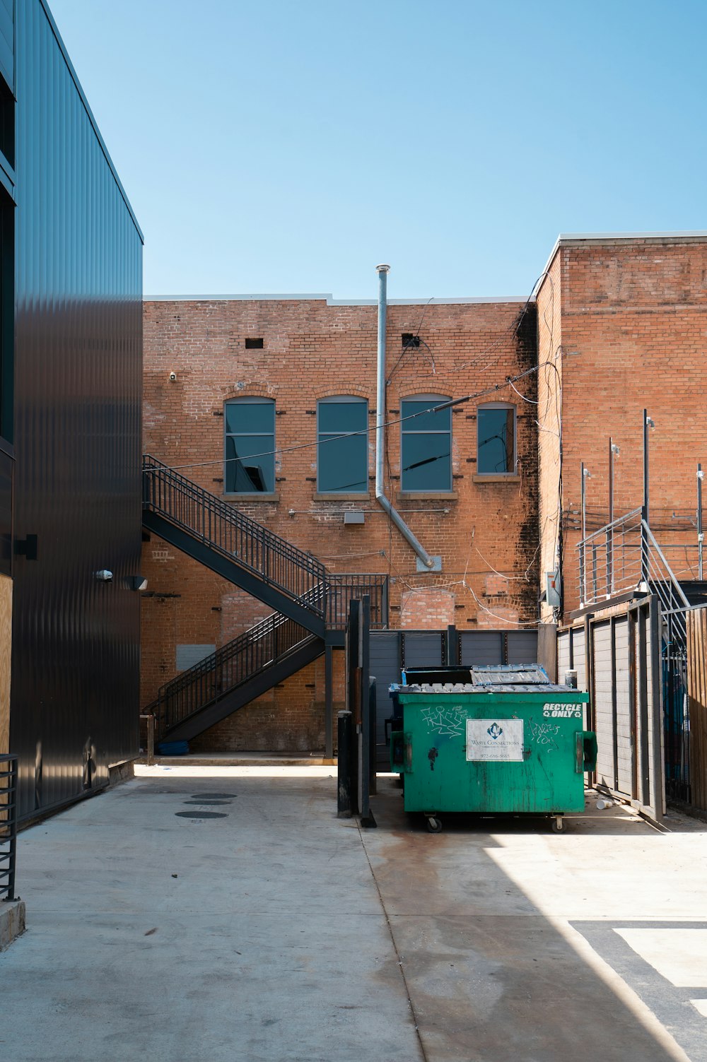green trash bin beside brown building