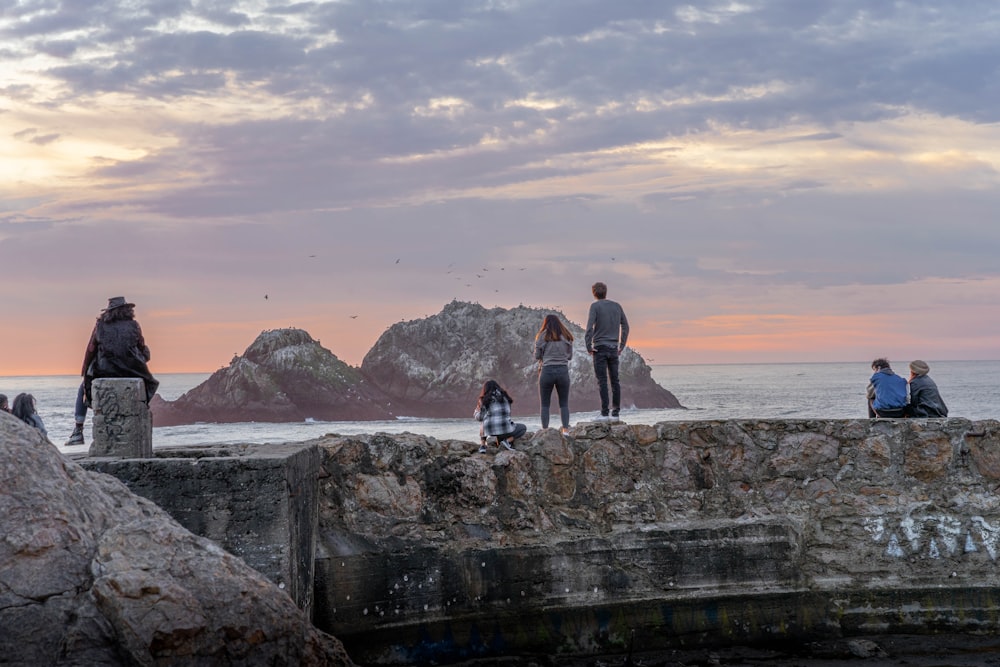 couple standing on rock formation near body of water during daytime