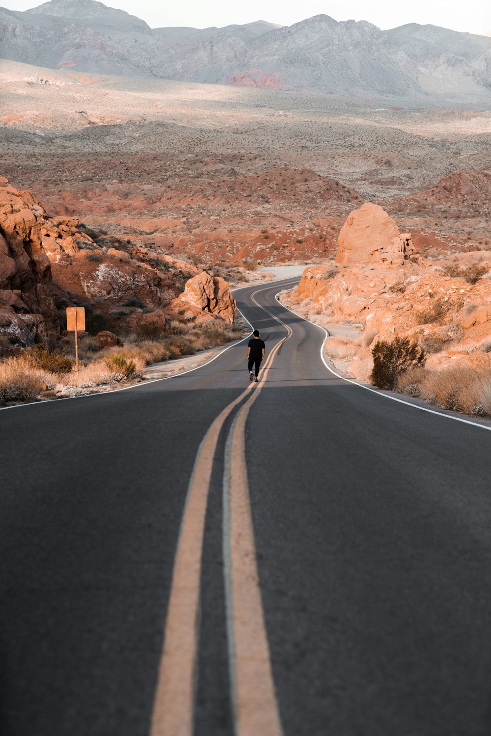 black asphalt road in between brown rock formation during daytime