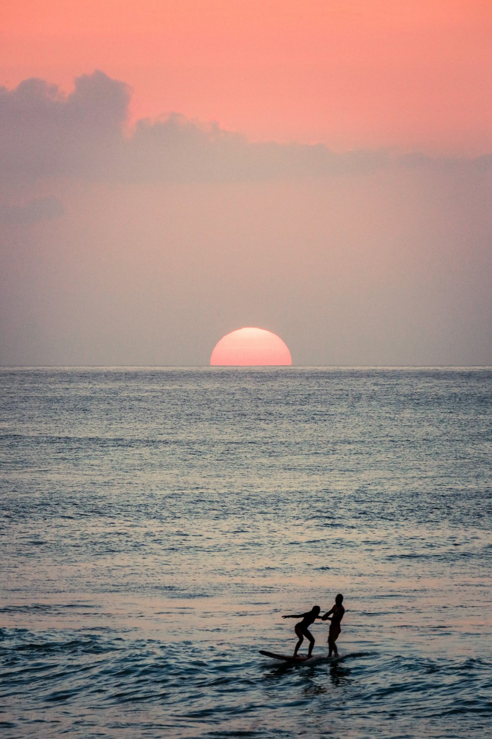 silhouette of person standing on sea shore during sunset