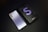 A sleek smartphone with a metallic finish lies beside its black box. The box features a large letter 'S' with the model name 'S21+ 5G' printed on it. The phone has a triple camera setup on the back and a minimalist design with the brand name visible.