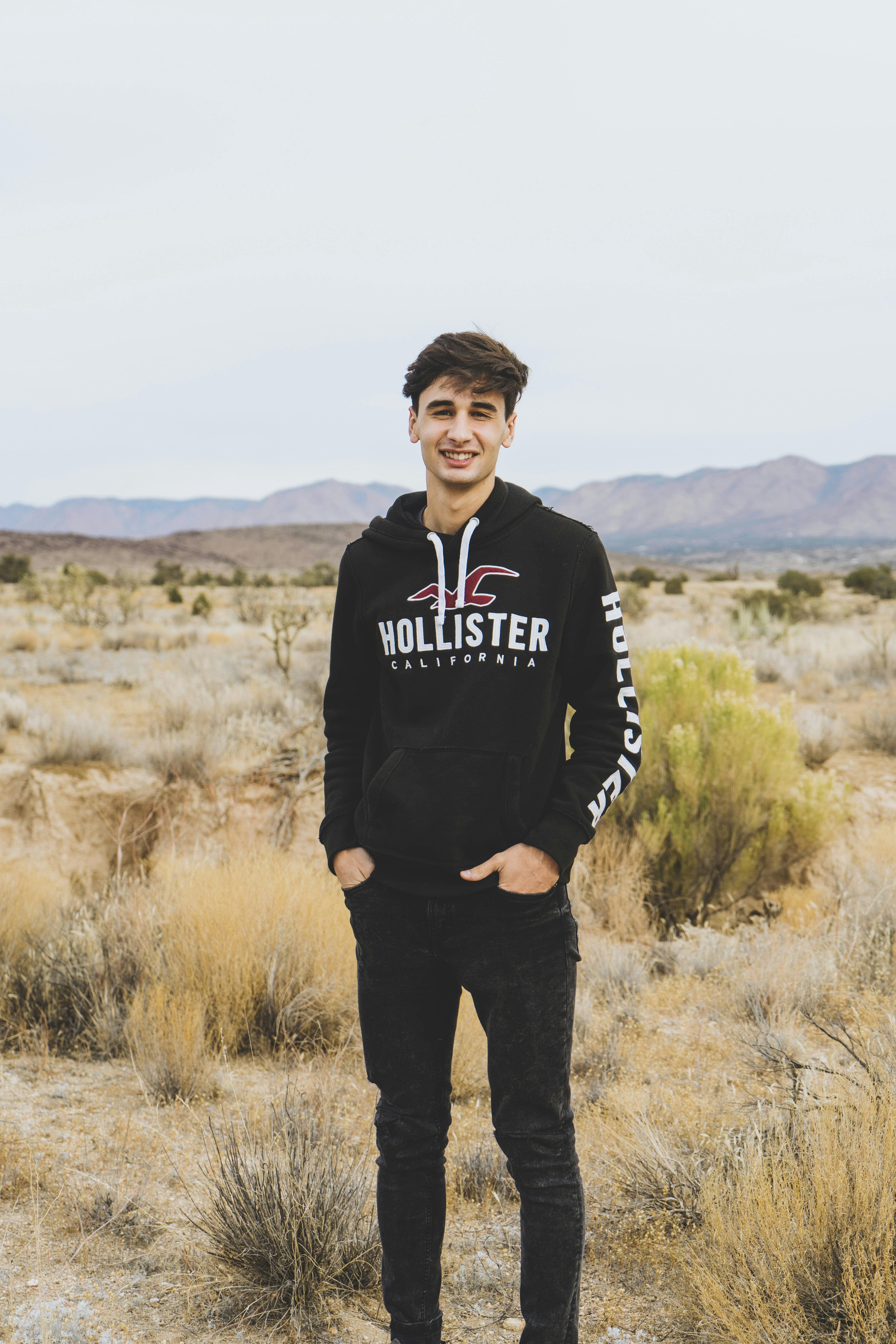 man in black and white adidas hoodie standing on brown grass field during daytime