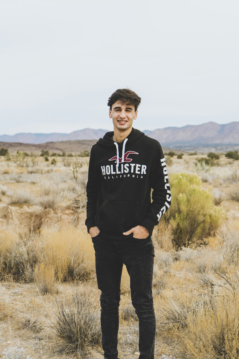 man in black and white adidas hoodie standing on brown grass field during daytime