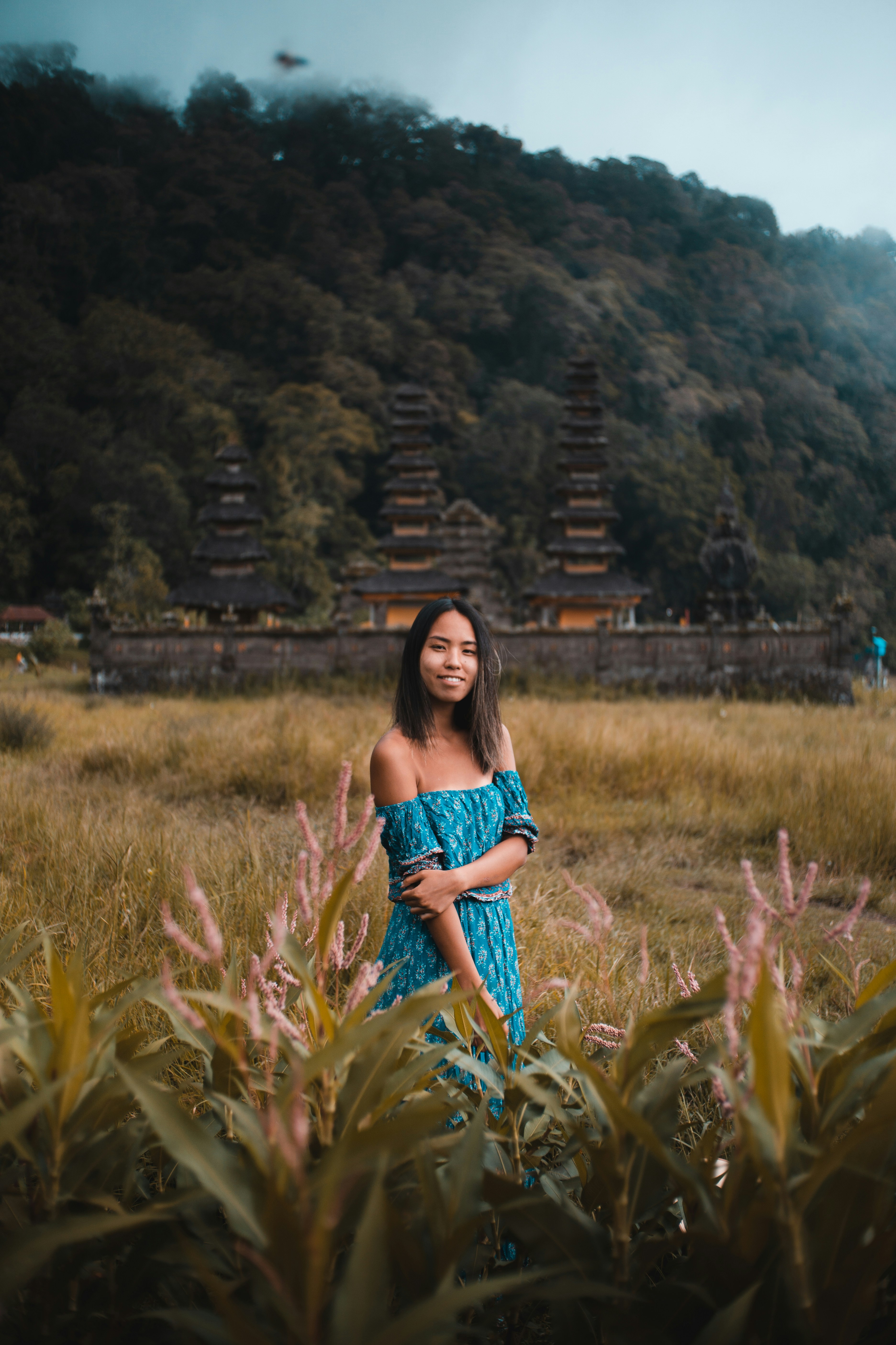 woman in blue denim dungaree standing on green grass field during daytime