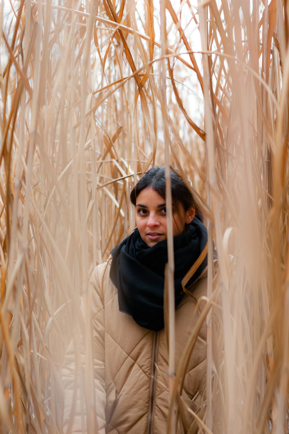 woman in black scarf and brown coat standing on wheat field during daytime