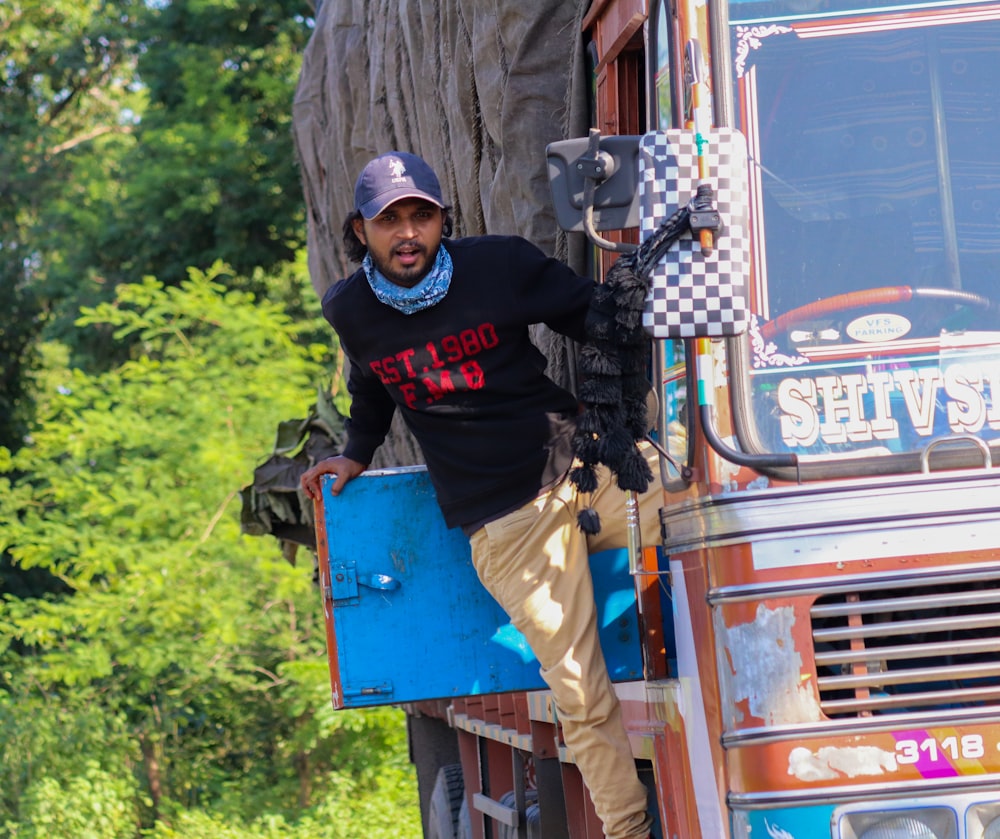 man in black long sleeve shirt and brown pants standing beside red truck during daytime