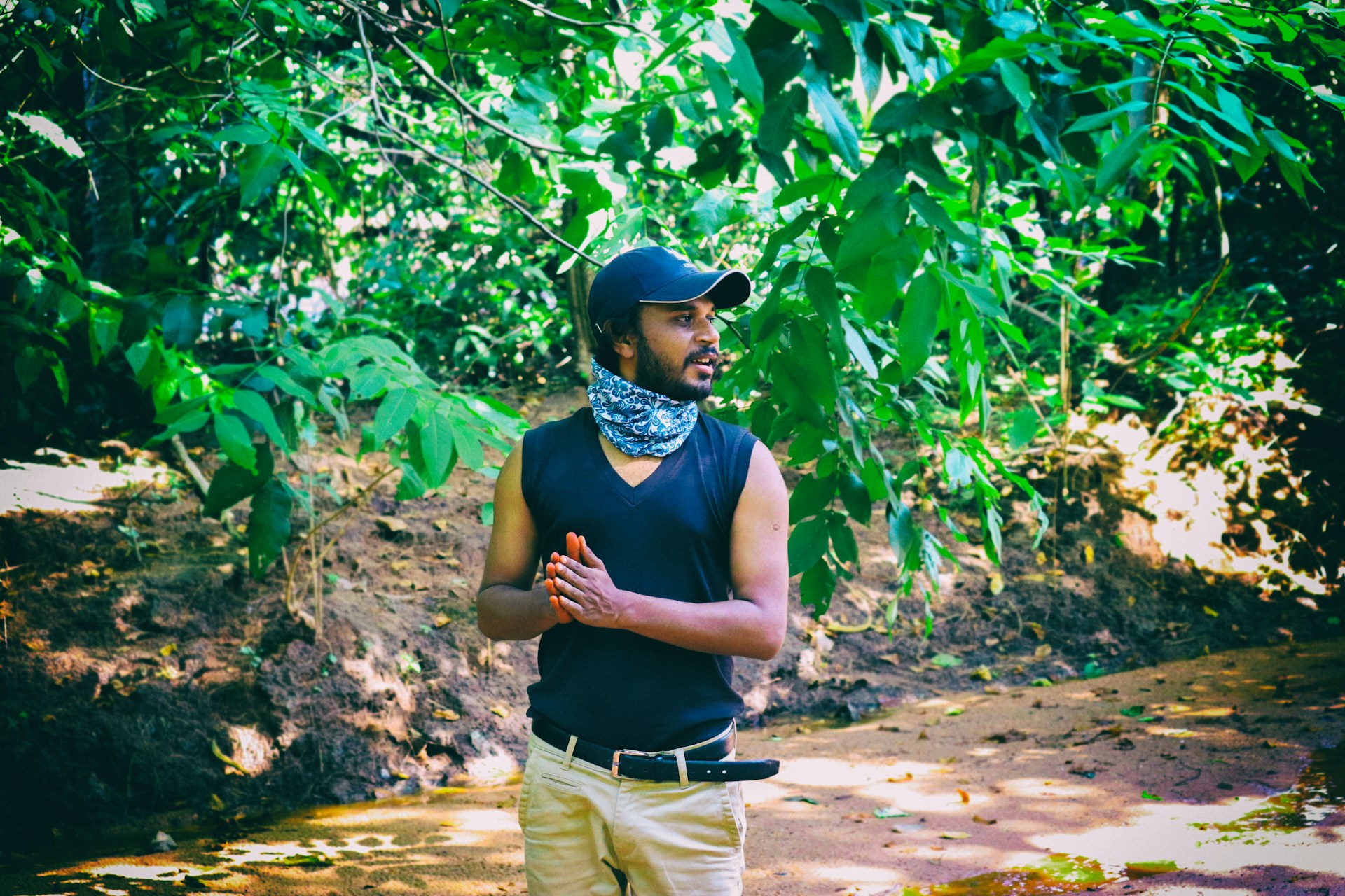 man in black tank top and beige pants standing near green plants during daytime
