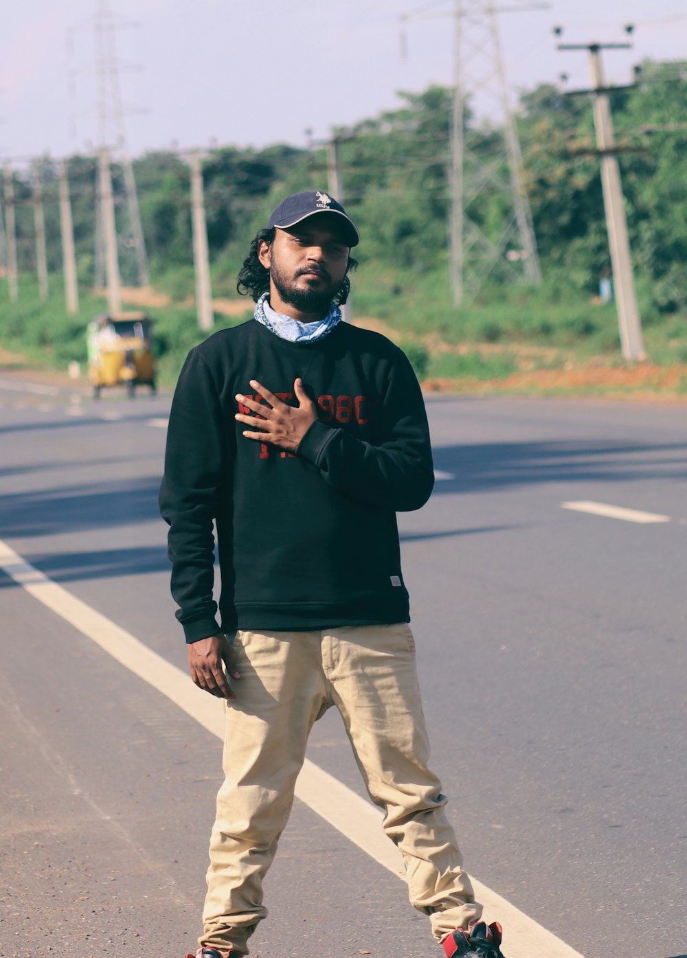 man in black long sleeve shirt and brown pants standing on road during daytime