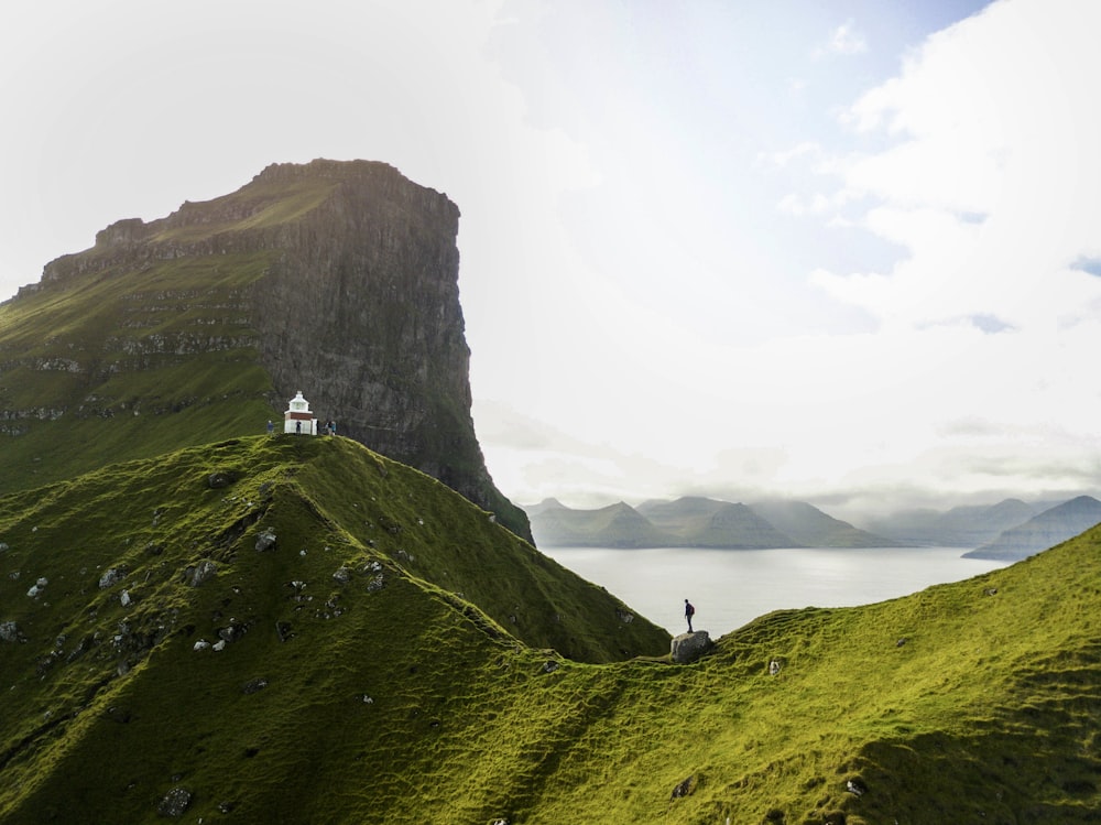 person standing on green mountain during daytime