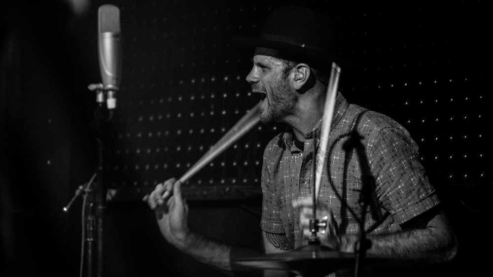 man in black and white plaid button up shirt playing drum