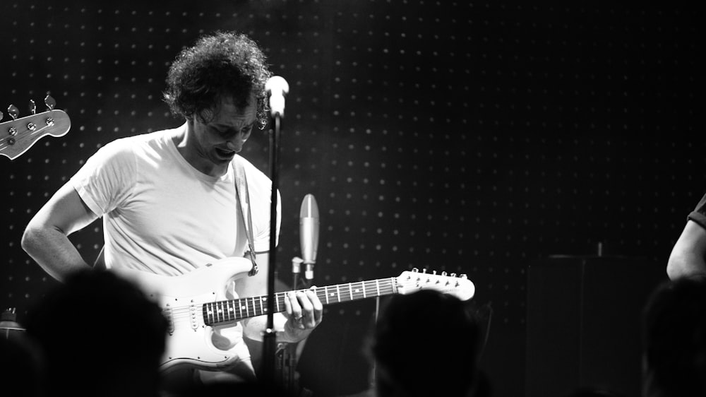 man in white crew neck t-shirt playing electric guitar