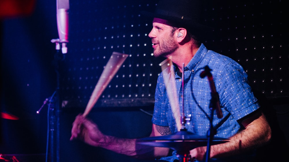 man in blue button up shirt playing drum
