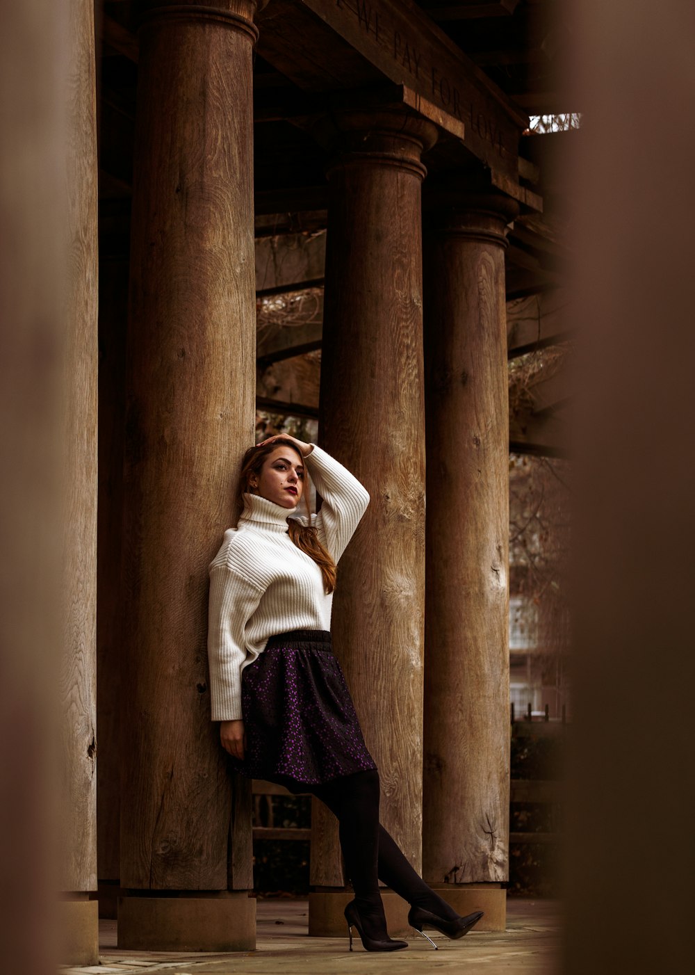 woman in white long sleeve shirt and red skirt standing on brown concrete post