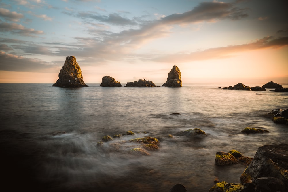 brown rock formation on sea under cloudy sky during daytime