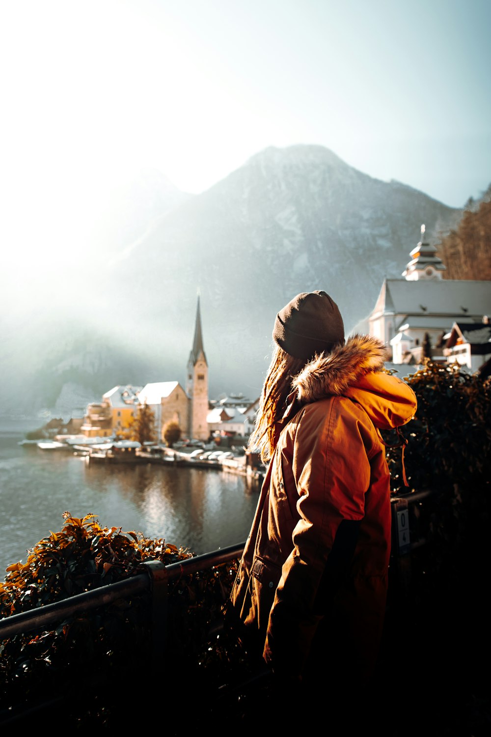 woman in orange jacket standing on brown wooden dock during daytime