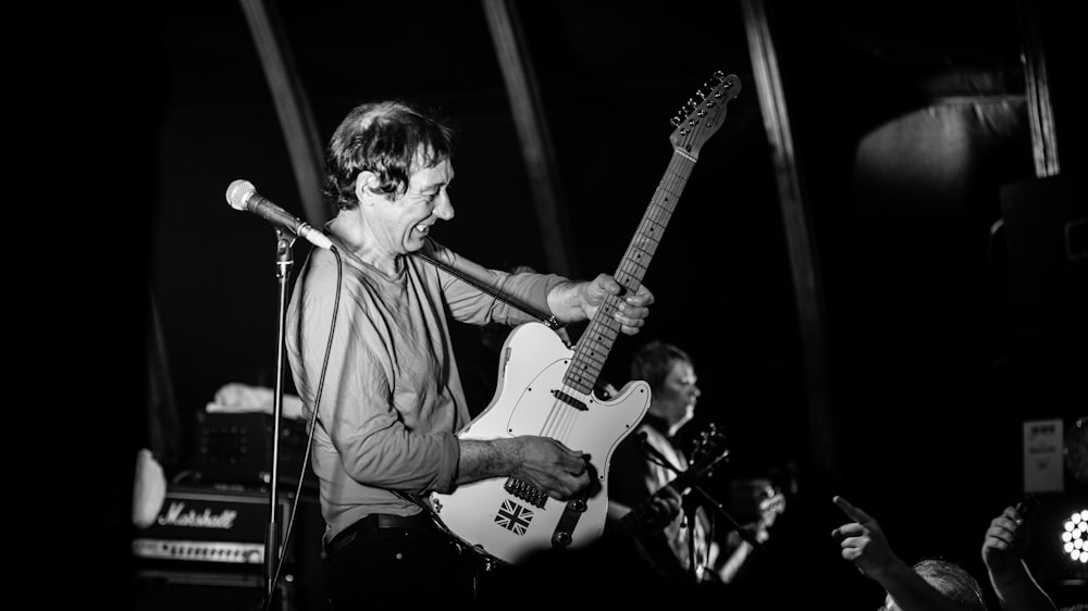 man in white long sleeve shirt playing electric guitar