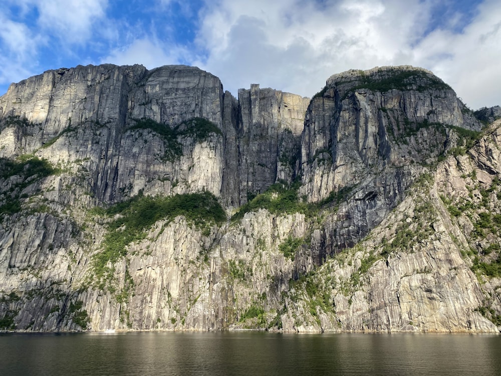 gray rocky mountain beside body of water during daytime