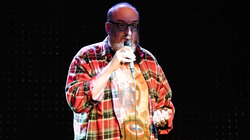 man in red and white plaid button up shirt holding microphone
