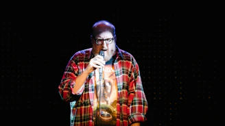 man in red white and black plaid button up shirt singing