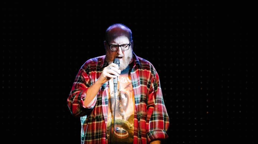 man in red white and black plaid button up shirt singing