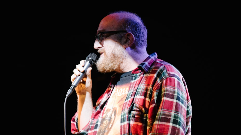 man in orange and white plaid button up shirt singing