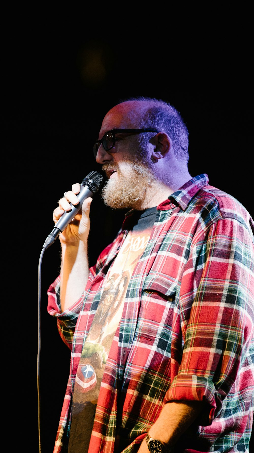 man in orange white and black plaid button up shirt holding microphone